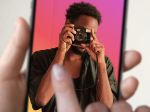 landscape photo of a black man taking a picture, overlaid with a portrait mode frame in instagram colors